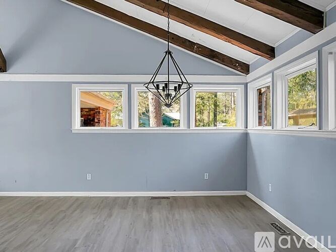 A room with wooden beams on the ceiling and a chandelier hanging from the center.