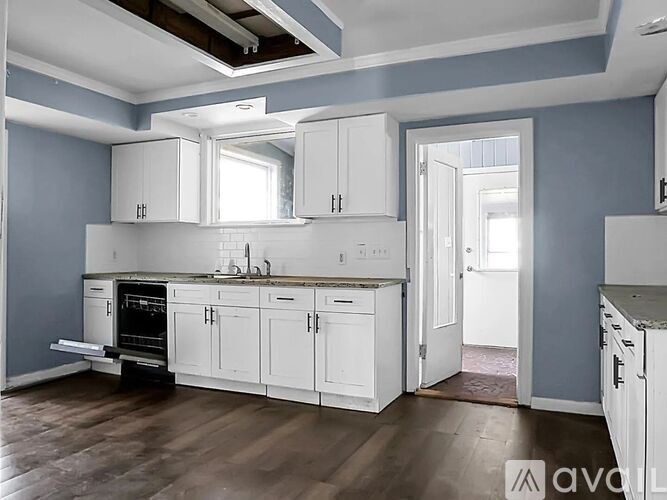 A kitchen with white cabinets and a wooden floor.