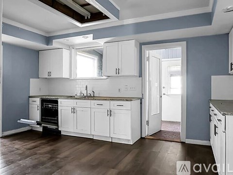 A kitchen with white cabinets and a wooden floor.