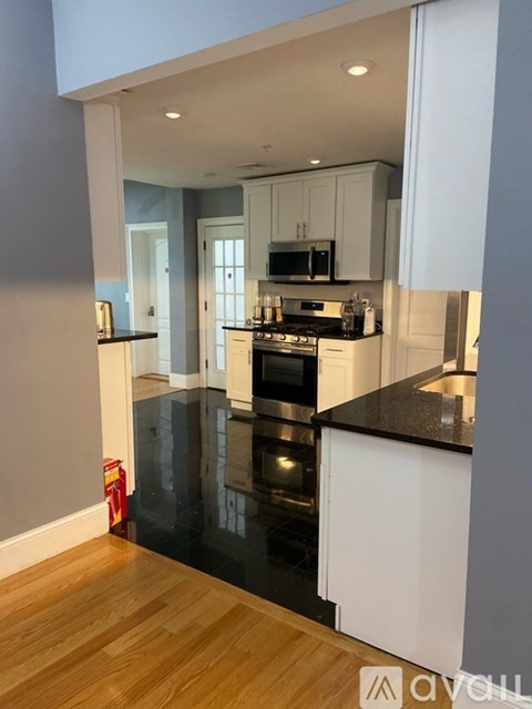 A kitchen with white cabinets and black countertops.