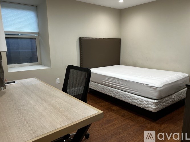 A bedroom with a bed, chair, and desk.