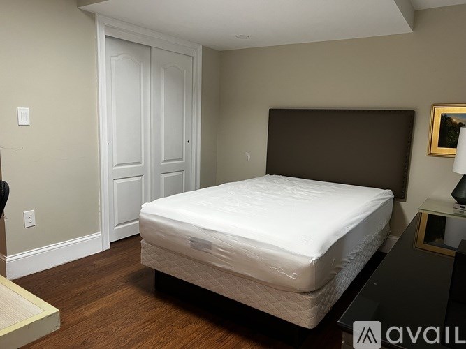 A bed with a white mattress is in a room with a brown headboard.