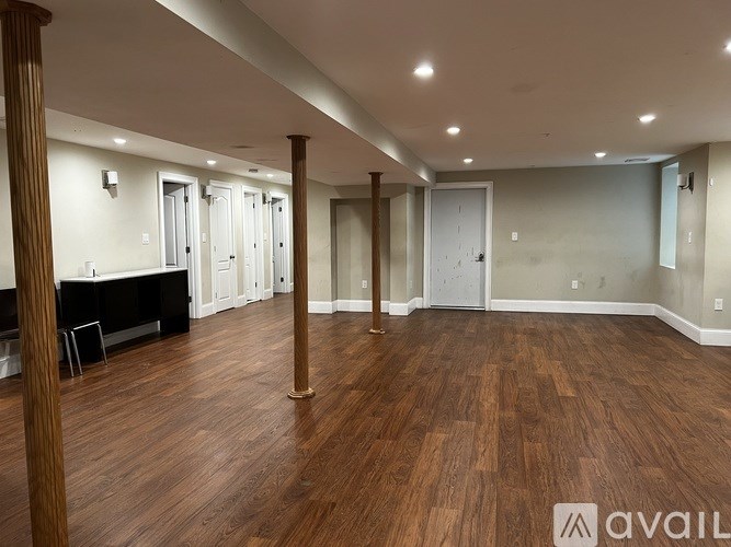 A spacious room with wooden floors and white walls.