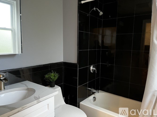 A bathroom with a white sink and black tiles.