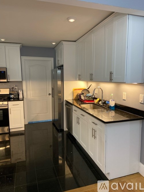 A kitchen with white cabinets and black countertops.