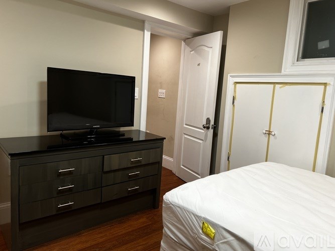 A bedroom with a bed, dresser, and television.