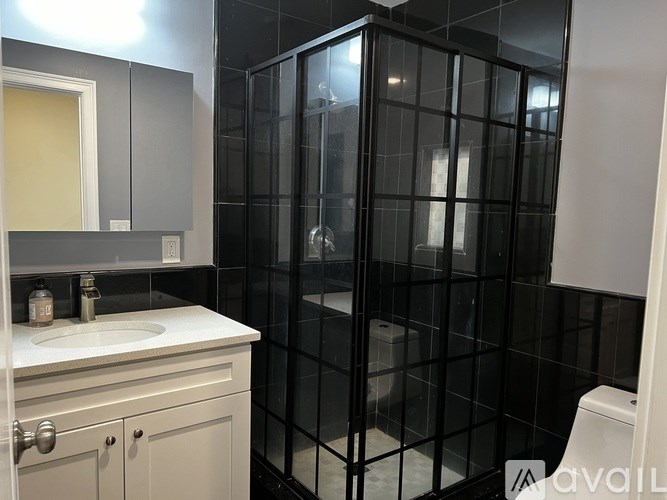 A bathroom with a white sink and a glass shower stall.