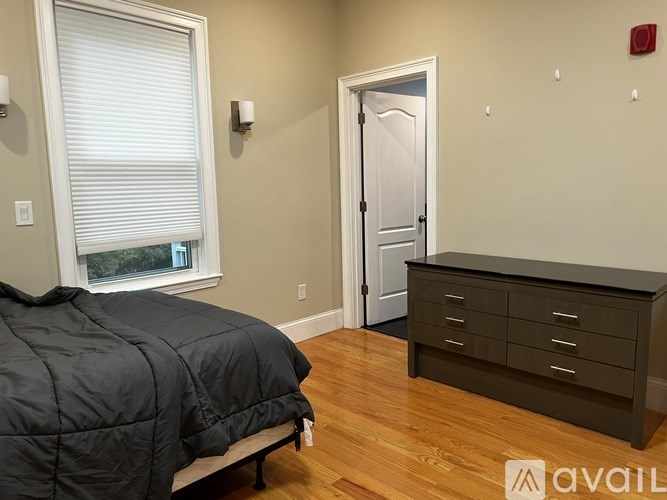 A bedroom with a bed, dresser, and window.