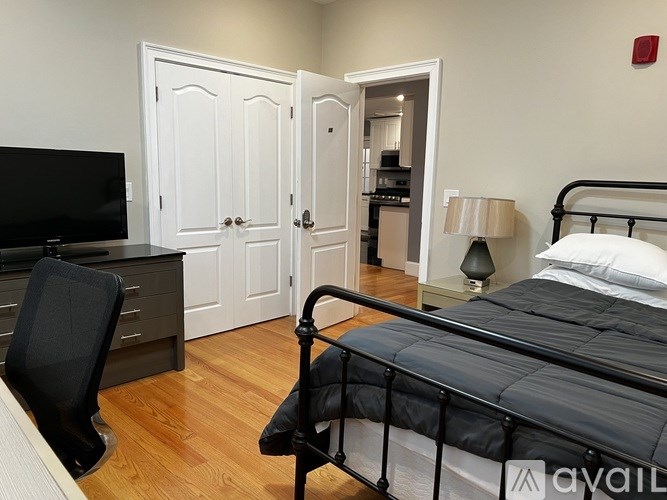 A bedroom with a bed, chair, and television.