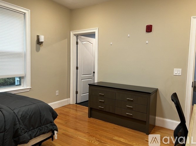 A room with a bed, a dresser, and a door.