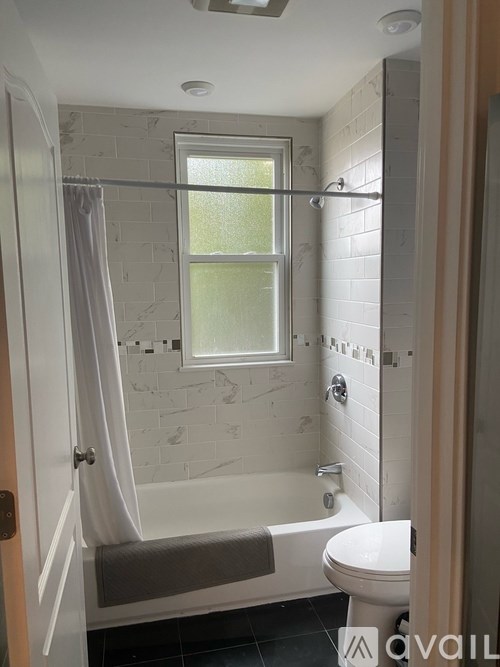 A bathroom with a toilet, tub, and window.