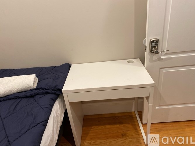 A white desk with a blue bed in the corner of a room.