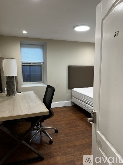 A room with a desk, chair, and bed.