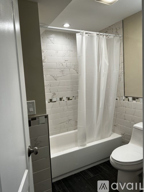 A bathroom with a white toilet and a white shower curtain.