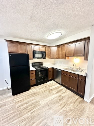 A kitchen with wooden cabinets and a black fridge.