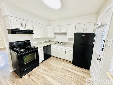 A kitchen with black appliances and white cabinets.