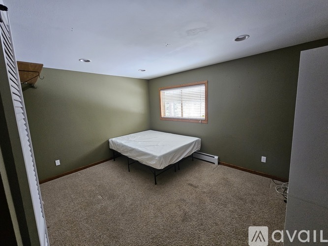 A bedroom with a bed, carpet, and a window.