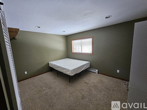 A bedroom with a bed, carpet, and a window.