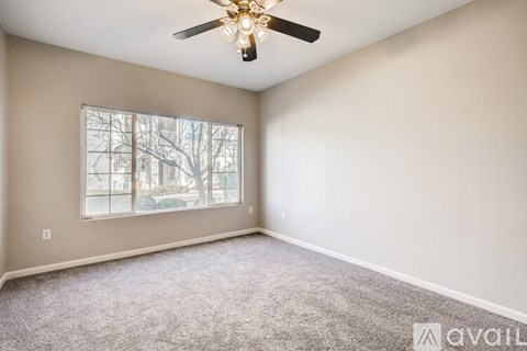 A room with a ceiling fan and a window showing a tree outside.