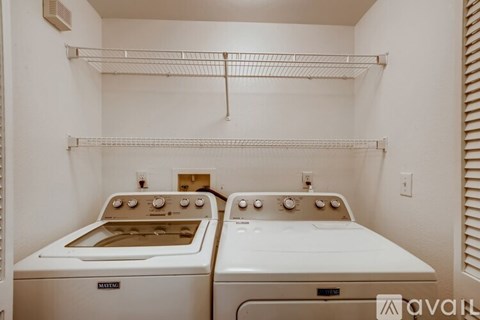A small kitchen with two ovens and a shelf above them.