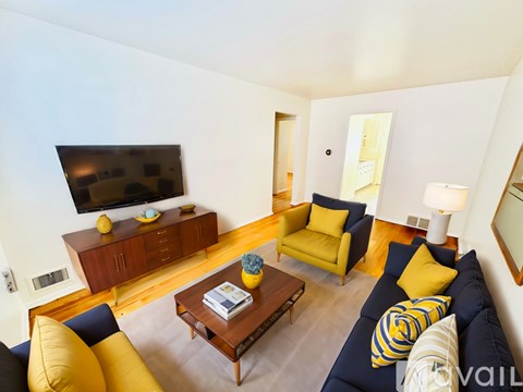 A living room with a blue couch and yellow pillows.