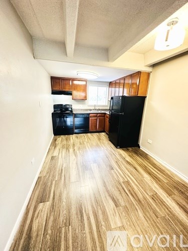 A kitchen with black appliances and wooden floors.