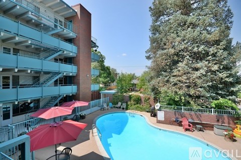 A pool area with red umbrellas and a building in the background.