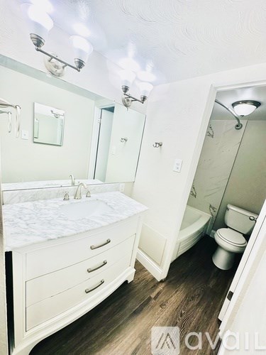 A white bathroom with a sink, toilet, and shower.