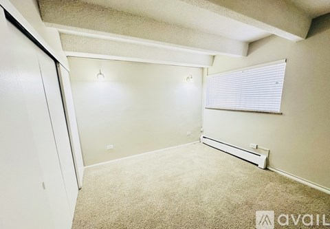 A room with a carpeted floor, a window with blinds, and a door.