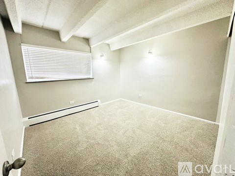A room with carpeted floor, a window with blinds, and a door.