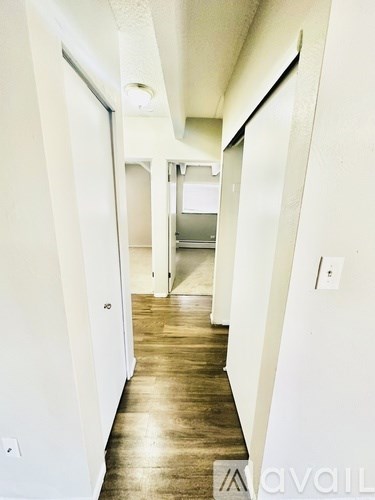 A long hallway with white walls and wood floors.