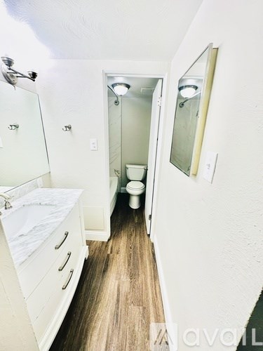 A bathroom with a toilet, sink, and mirror.