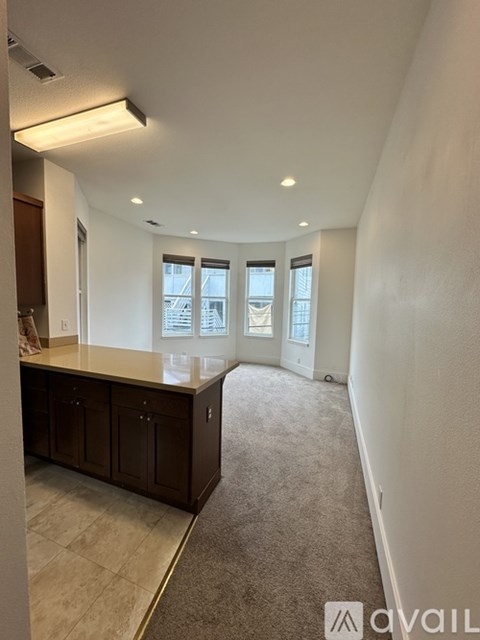 A spacious room with a kitchen area and carpeted floor.
