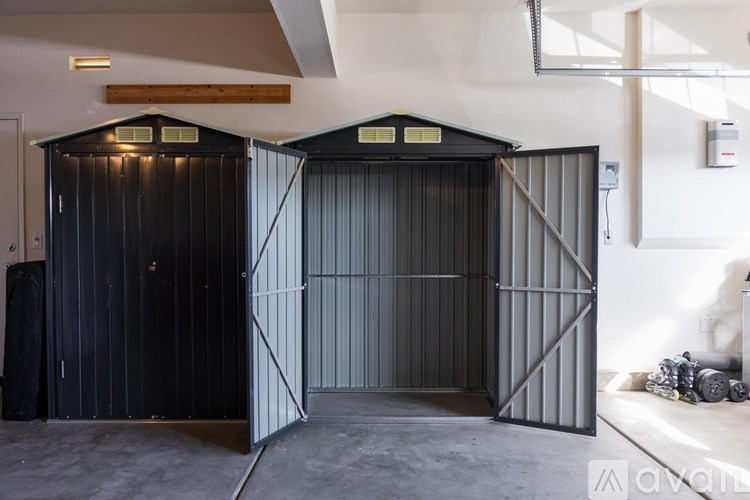 Two black metal storage sheds in a garage.