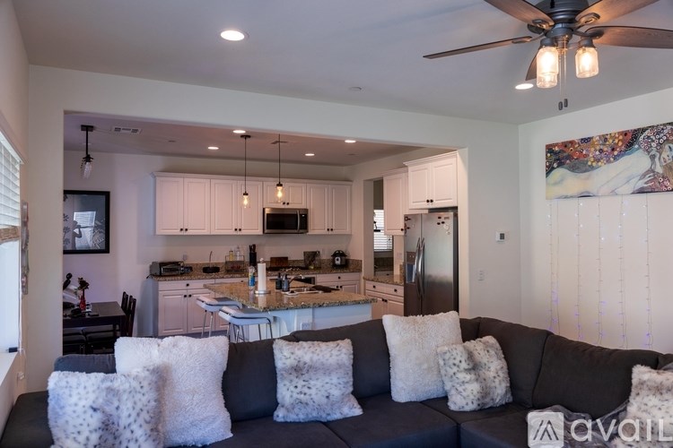 A modern kitchen with a large island and a ceiling fan.