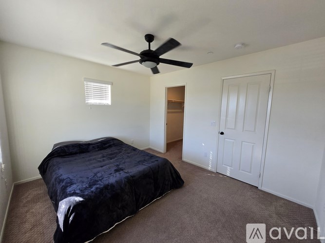 A bedroom with a bed, ceiling fan, and carpeted floor.