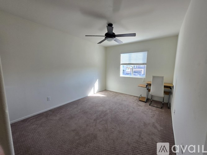 A room with a ceiling fan and a window with blinds.