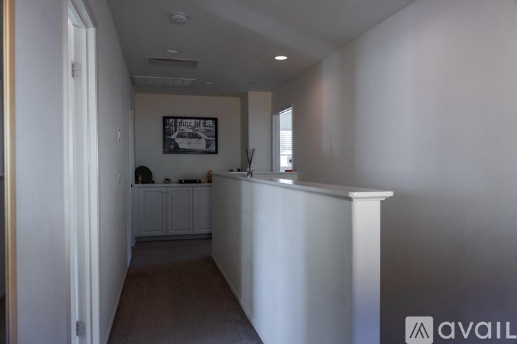 A hallway with a white railing and a framed picture on the wall.