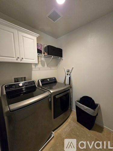 A kitchen with a stainless steel dishwasher and oven, a black trash bag, and a white cabinet with a microwave on top.