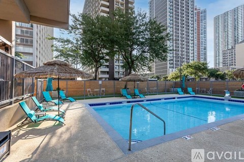 A swimming pool with lounge chairs and a thatched roof structure.