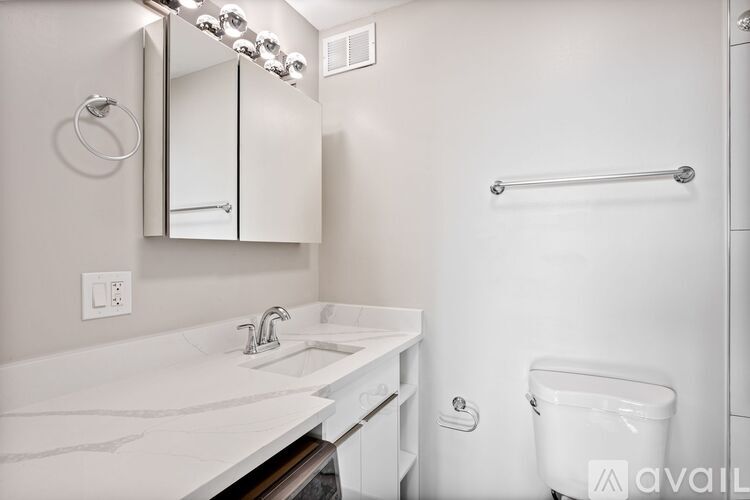 A white bathroom with a sink, mirror, and toilet.