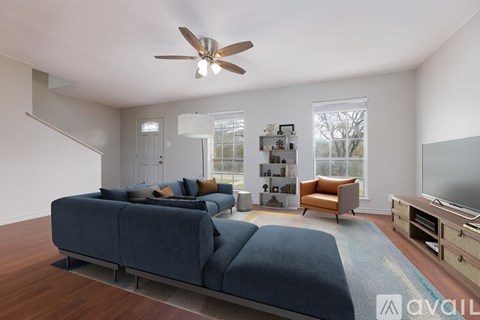 A living room with a blue couch and a ceiling fan.