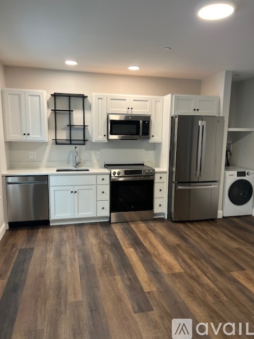 A kitchen with white cabinets and a wooden floor.