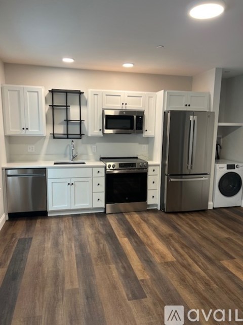 A kitchen with white cabinets and a wooden floor.