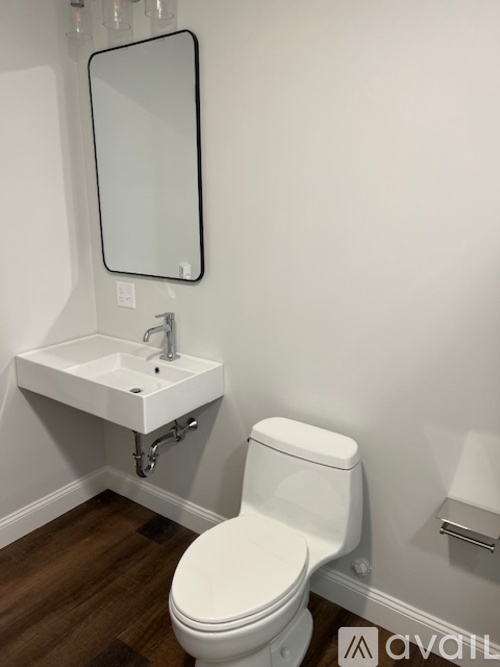 A white toilet with a sink and mirror in a bathroom.