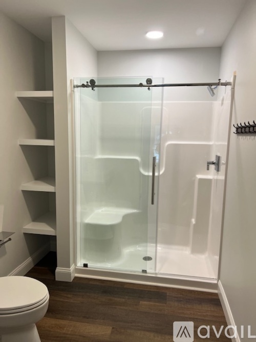 A white toilet is in a small bathroom with a walk-in shower.