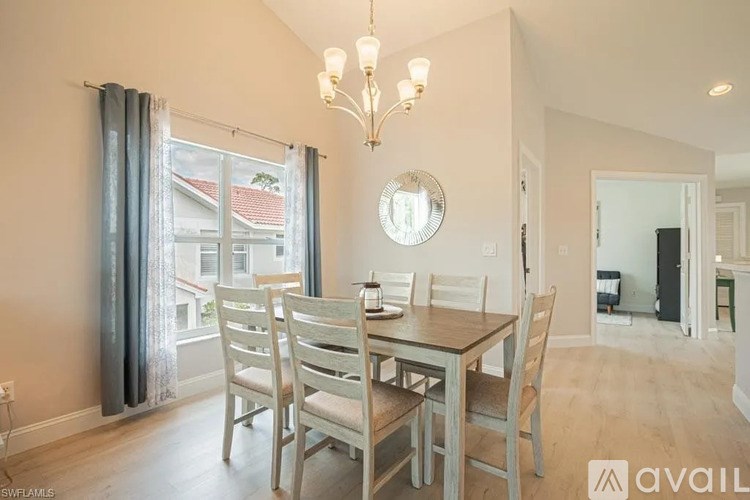 A dining room with a table set for four and a chandelier hanging from the ceiling.