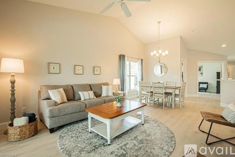 A living room with a grey couch, a wooden coffee table, and a dining table with chairs.