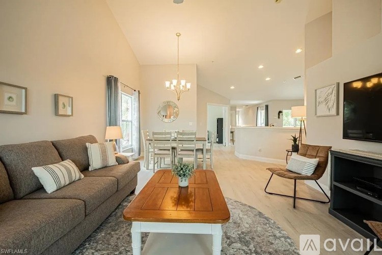 A living room with a grey couch, a wooden coffee table, and a chandelier.