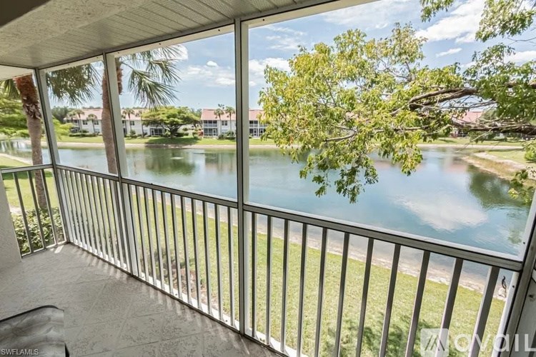 A balcony overlooks a body of water with a tree in the foreground.